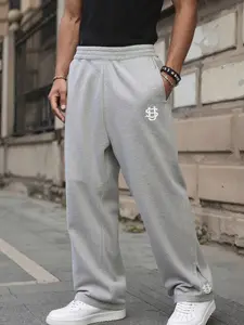 One men’s jogger sweatpants with embroidered letters—urban casual style. High-rise drawstring waist paired with white embroidered letters on the pant body and hem. Soft knit fabric drapes comfortably, and the loose wide fit flatters the legs. Suitable for