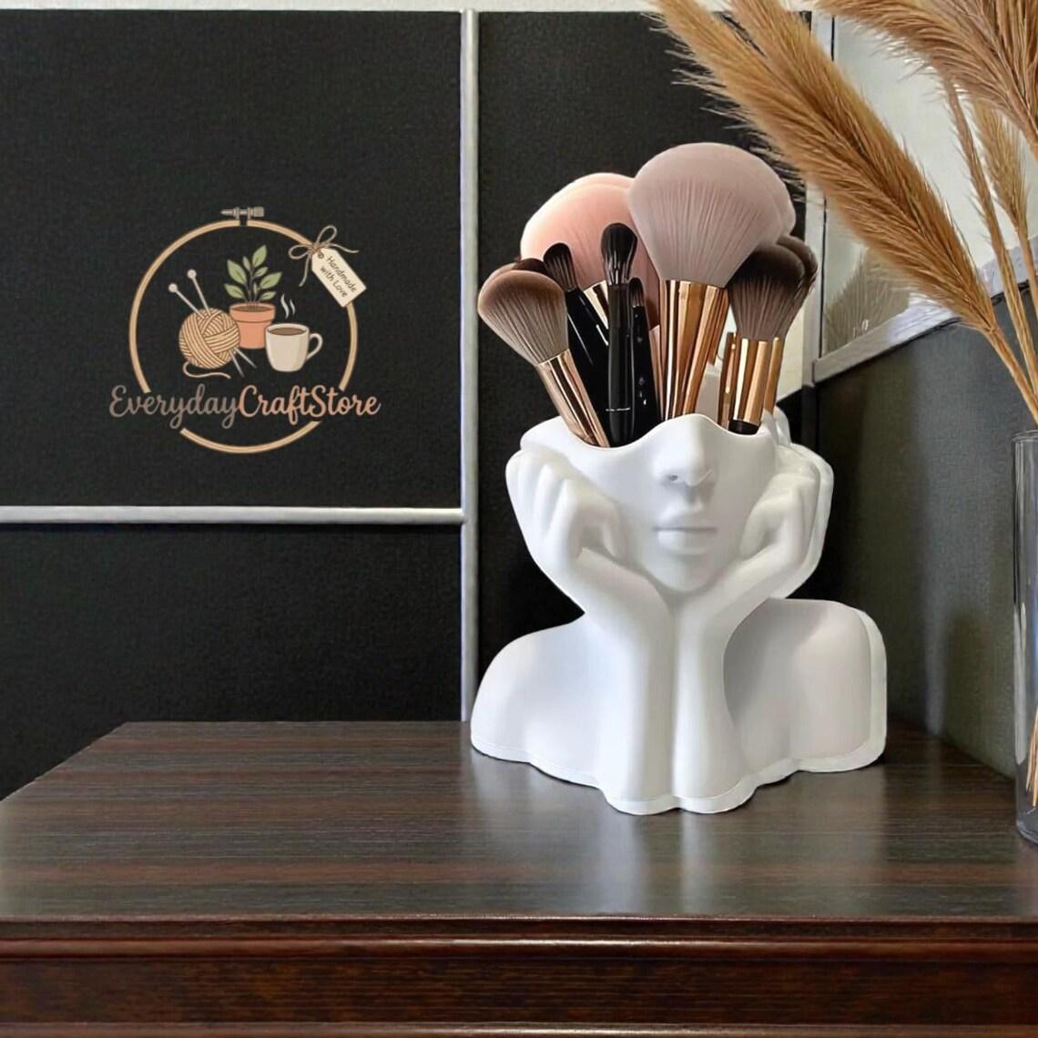 A Cute Makeup Brush Storage Box Shaped Like a Human Face • Featuring a Minimalist White Design That Captures The Relaxed Vibe of a Resting Face • This Artistic Piece for Your Desk Combines Practicality with Aesthetic Appeal