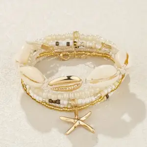 Coastal bracelet stack - gold and white beaded bracelet stack with starfish and shell charms.