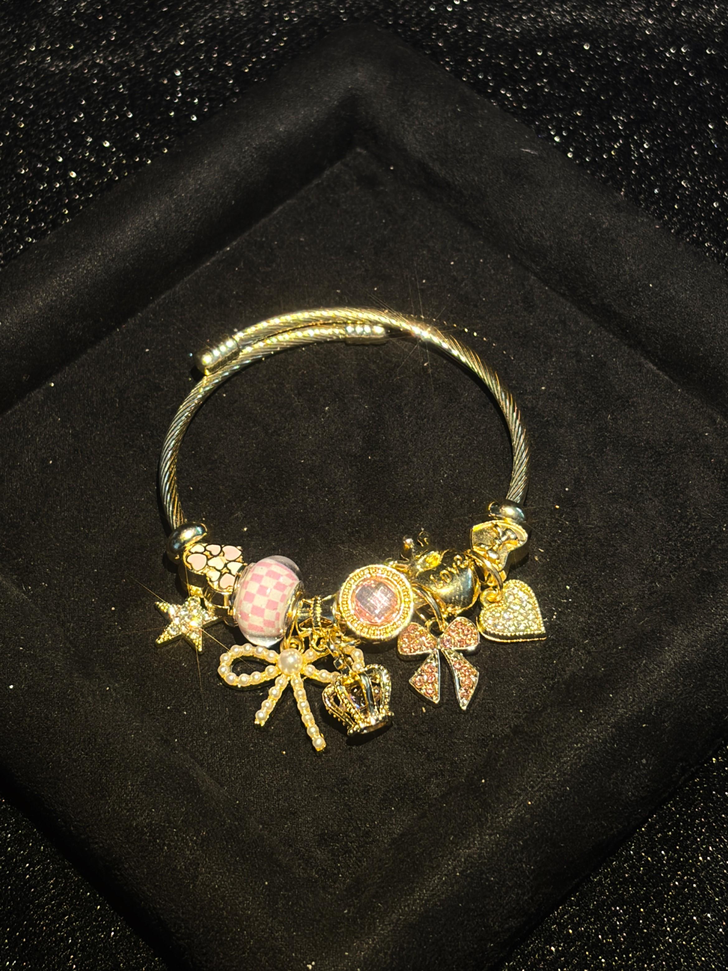 Women's Cute Princess-Style Gold-Tone Adjustable Cable Bangle with Pink Checkered Bead, Bow, Crown, and Heart Dangle Charms Women's Cute Princess-Style Gold-Tone Adjustable Cable Bangle with Pink Checkered Bead, Bow, Crown, and Heart Dangle Charms