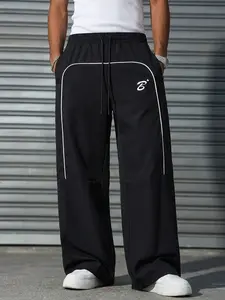 Men’s black wide-leg track pants with curved white piping and letter print, elastic waistband with drawstring, streetwear trousers