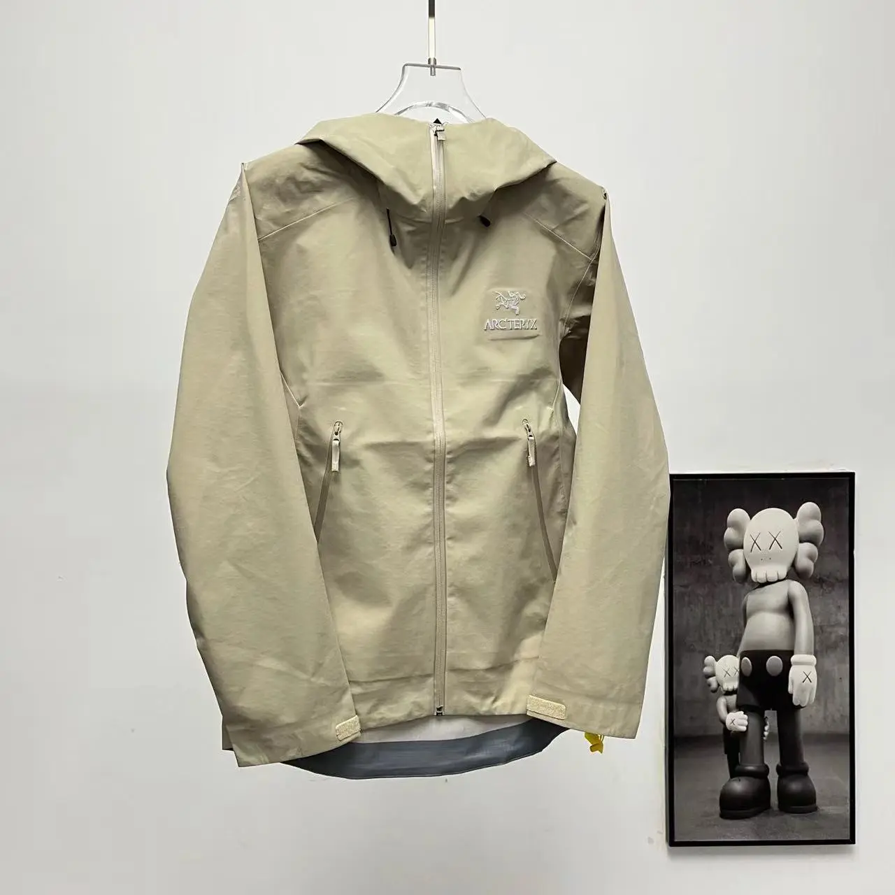 Neutral beige lightweight hooded rain jacket weather‑resistant material sealed zipper pockets adjustable cuffs great for mountain trips and casual street outfits