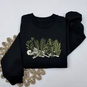 Print Sweatshirt with Highly Detailed Skeleton and Botanical Graphic. This bold oversized top features a complex illustration of a human form intertwined with lush tropical foliage, creating a statement piece for streetwear enthusiasts.