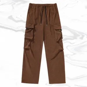 A pair of coffee colored corduroy multi pocket work pants, featuring a retro trendy style with drawstring waist details that are both vintage and fashionable. The large side pockets cleverly combine retro workwear with trendy elements. Made of corduroy ma