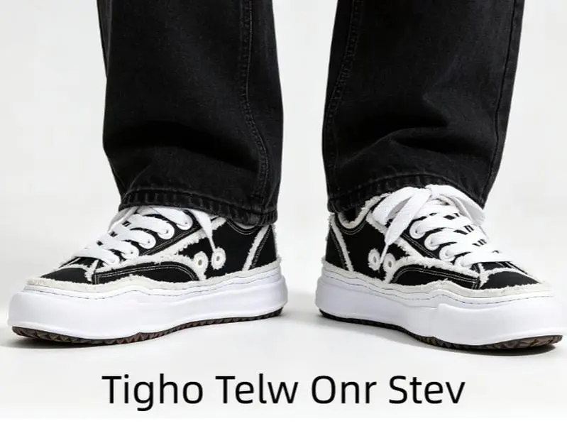 This black canvas low-top shoe with frayed white raw edges and block white sole matches casual shorts to make bold sketch-style street fits for city outdoor hangouts
