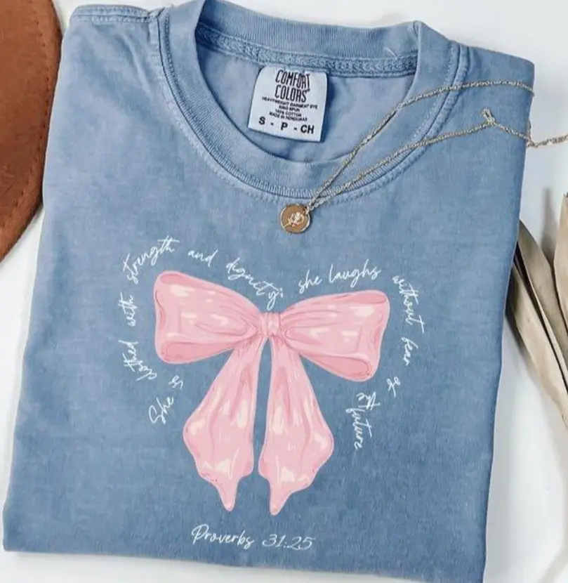 ~Comfort Colors~ She Is Clothed With Strength Proverbs Coquette T-Shirt, Bible Verse Shirt For Her Cute Christian Gift, Coquette Bow Pink Graphic Tee