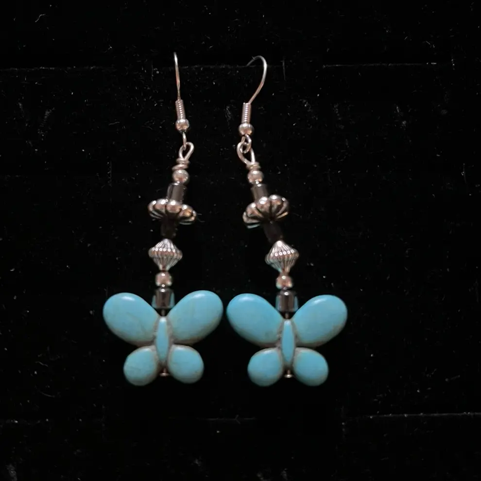 Navajo handmade sterling silver hook earrings featuring magnesite turquoise butterfly-shaped beads, hematite, silver daisy-shaped beads and hogan style beads.