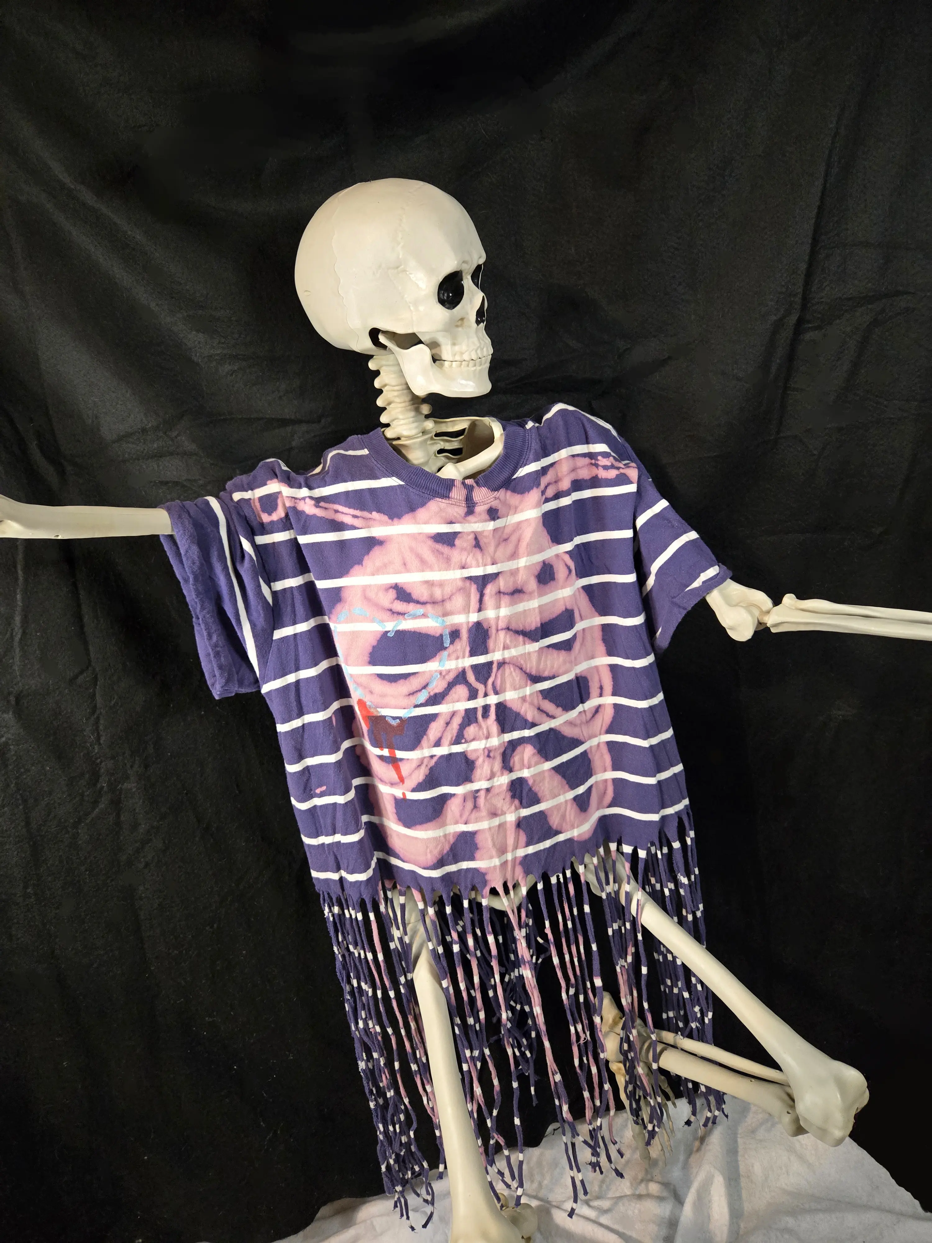 Striped blue and white fringed upcycled top with a graphic skeleton rib cage on the front and a spine back design of cut and knots on the back.