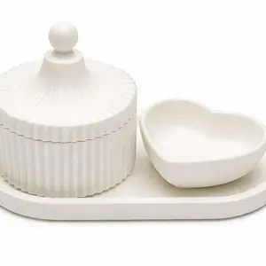 Elegant white ceramic set featuring a ribbed lidded jar and a heart-shaped bowl on a matching tray. Designed for tabletop organization and stylish display. Smooth white finish complements neutral and modern decor.