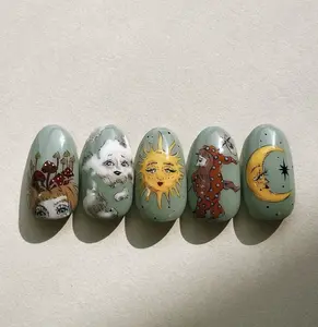 Whimsical celestial nails with hand-painted sun, moon, clouds, and mushroom motifs on sage green base for a dreamy vintage fairy-tale aesthetic