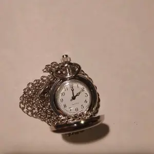 golden necklace-pocket watch with a USA and  in god we trust reading. hold the top and it opens to a small clock