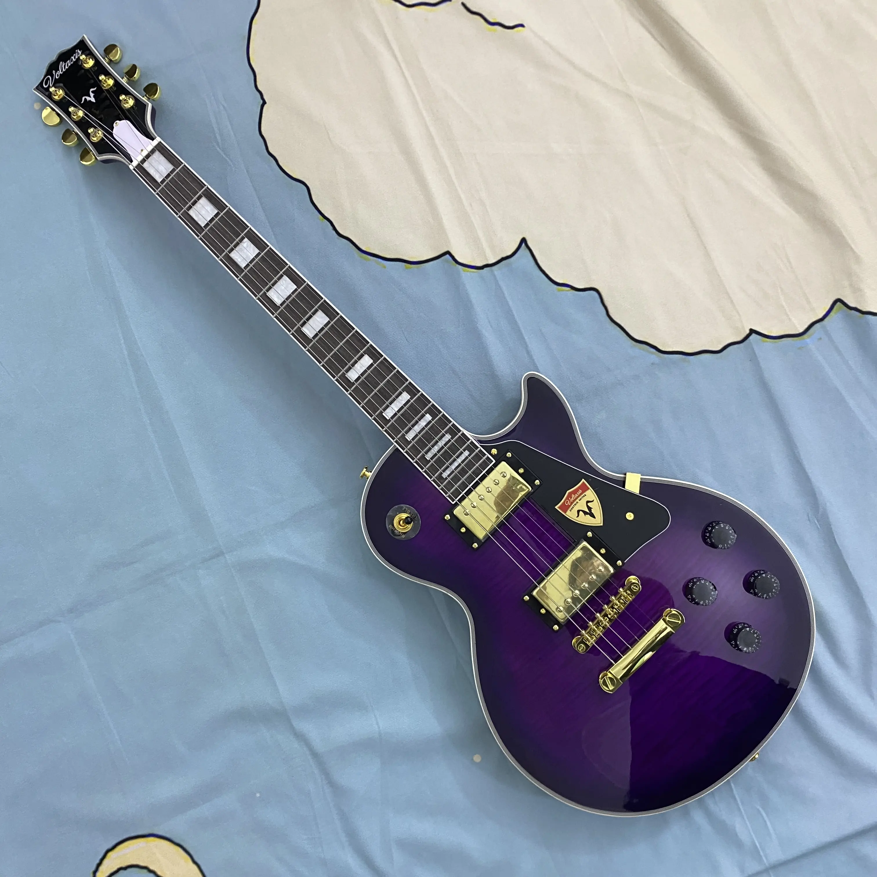 Purple 6-string LP electric guitar with mahogany body， gold hardware， rosewood fretboard, white binding, 22 frets. The headstock has removable stickers.