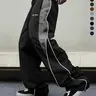 Men’s black wide-leg casual athletic pants made from wrinkle-resistant woven fabric, featuring a drapey long floor-length cut, an elastic wide drawstring waist, and clean, extended wide legs; suitable for campus commuting and Korean high-street street sty