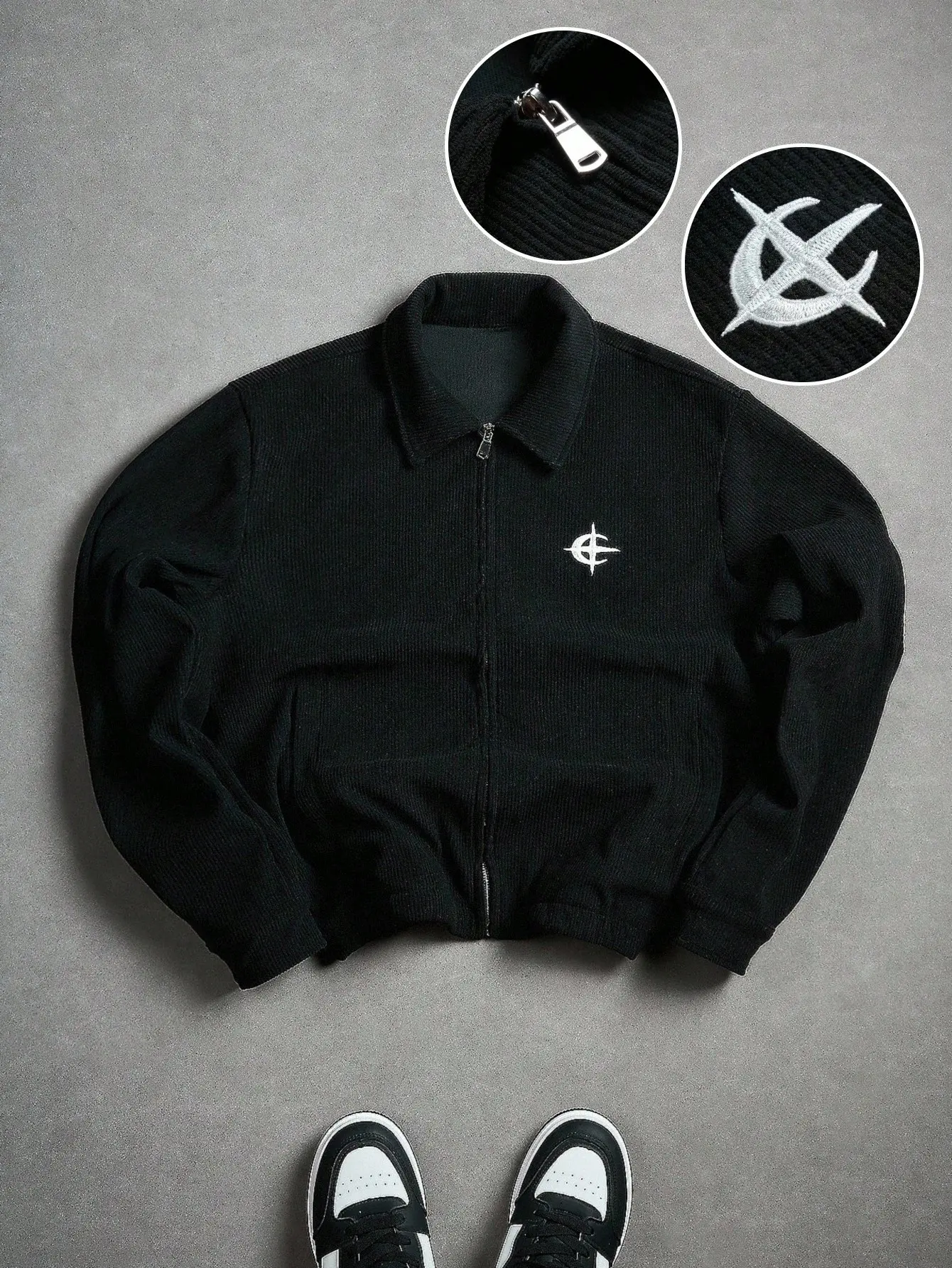 Men’s black cropped zip-up jacket with vertical ribbed detailing and a stand collar, featuring an embroidered small logo on the chest and an elasticated hem; slim-fit cardigan outerwear.