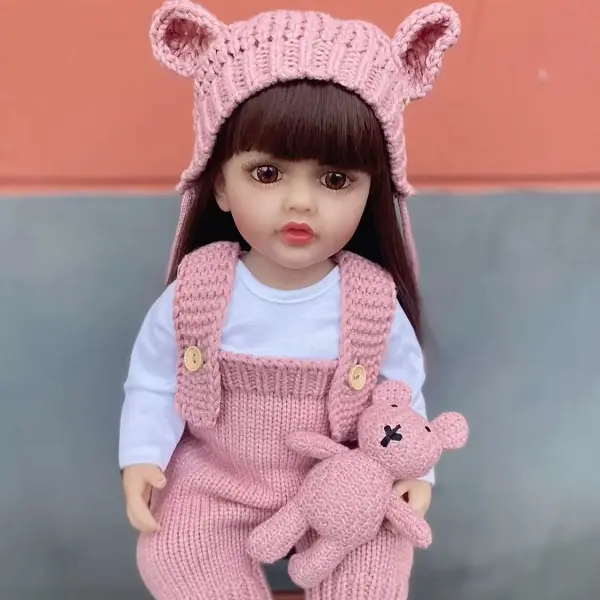 22 inch lifelike newborn baby girl doll, soft vinyl long hair doll, equipped with handmade pink bear ear knitted hat, camisole and matching small knitted bear toy, perfect birthday and Christmas gift for girl doll collectors
