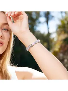 Pink crystal XOXO bracelet, available in silver and rose gold, featuring a classic XOXO design and sparkling pink crystals. Suitable for various styles of clothing.