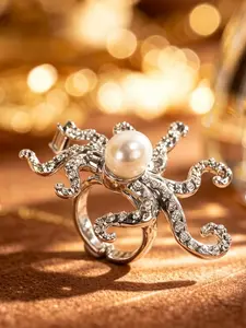 A silver octopus shaped ring featuring marine creatures, with a large central pearl paired with colored diamonds on the tentacles, suitable for wearing in dark or retro fashion, artistic events, and other settings.