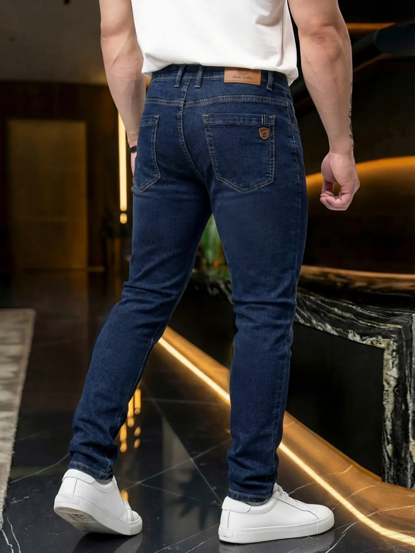 Four-season men's stretch slim-fit jeans, featuring a tailored slim cut with an exquisitely crafted brown leather label. These are business casual jeans suitable for daily office wear.