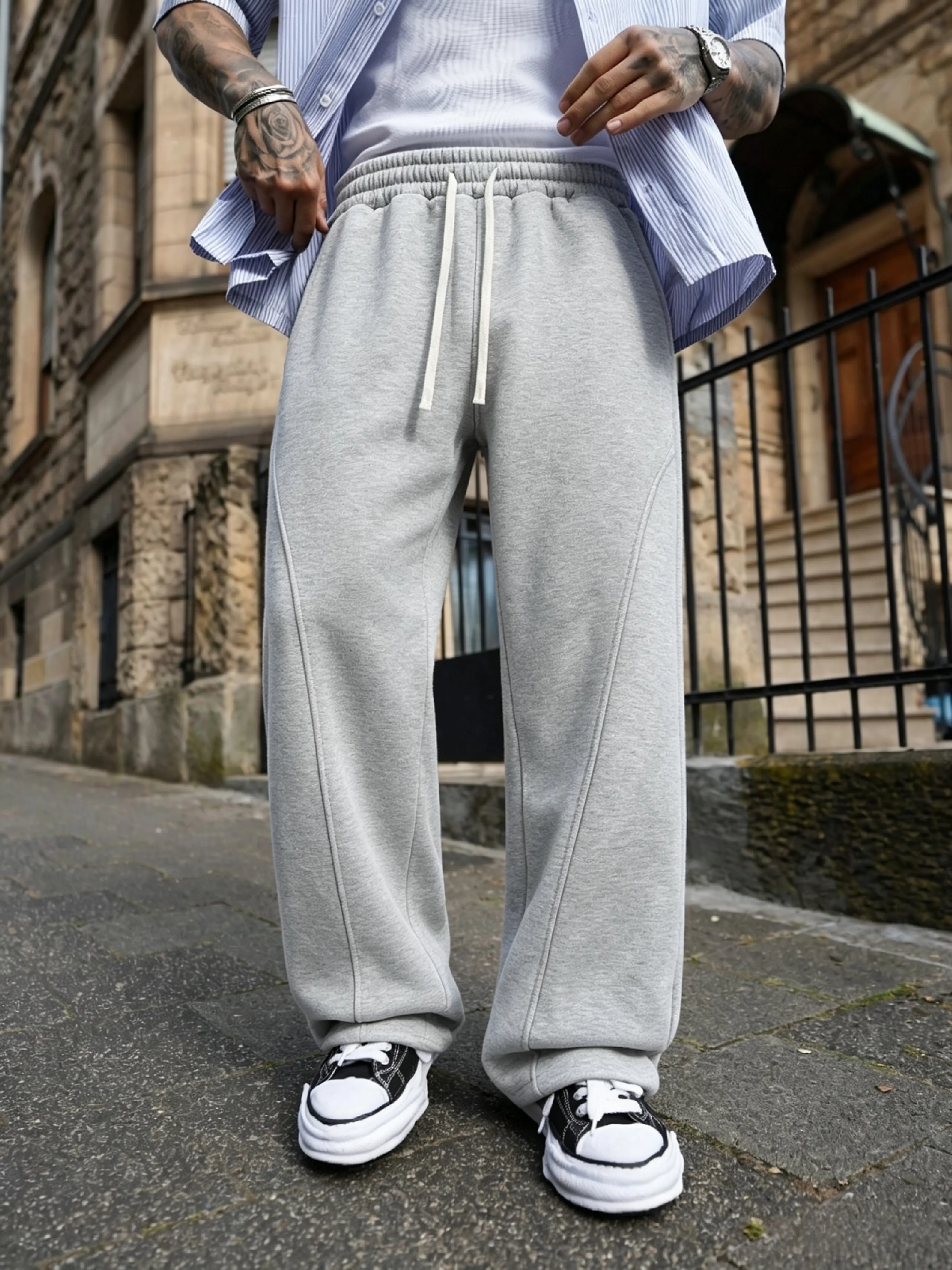Men’s jogger sweatpants with a diagonal split design, elastic drawstring waistband, loose straight-leg long pants, suitable for casual wear in spring and autumn.