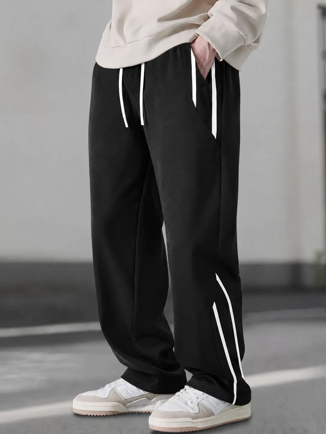 One men’s knit straight-leg pants with a drawstring, urban casual style featuring black-and-white striped contrast paired with an extended white drawstring and a drapey knit fabric; suitable for commuting, shopping, and exploring stores—relaxed, versatile