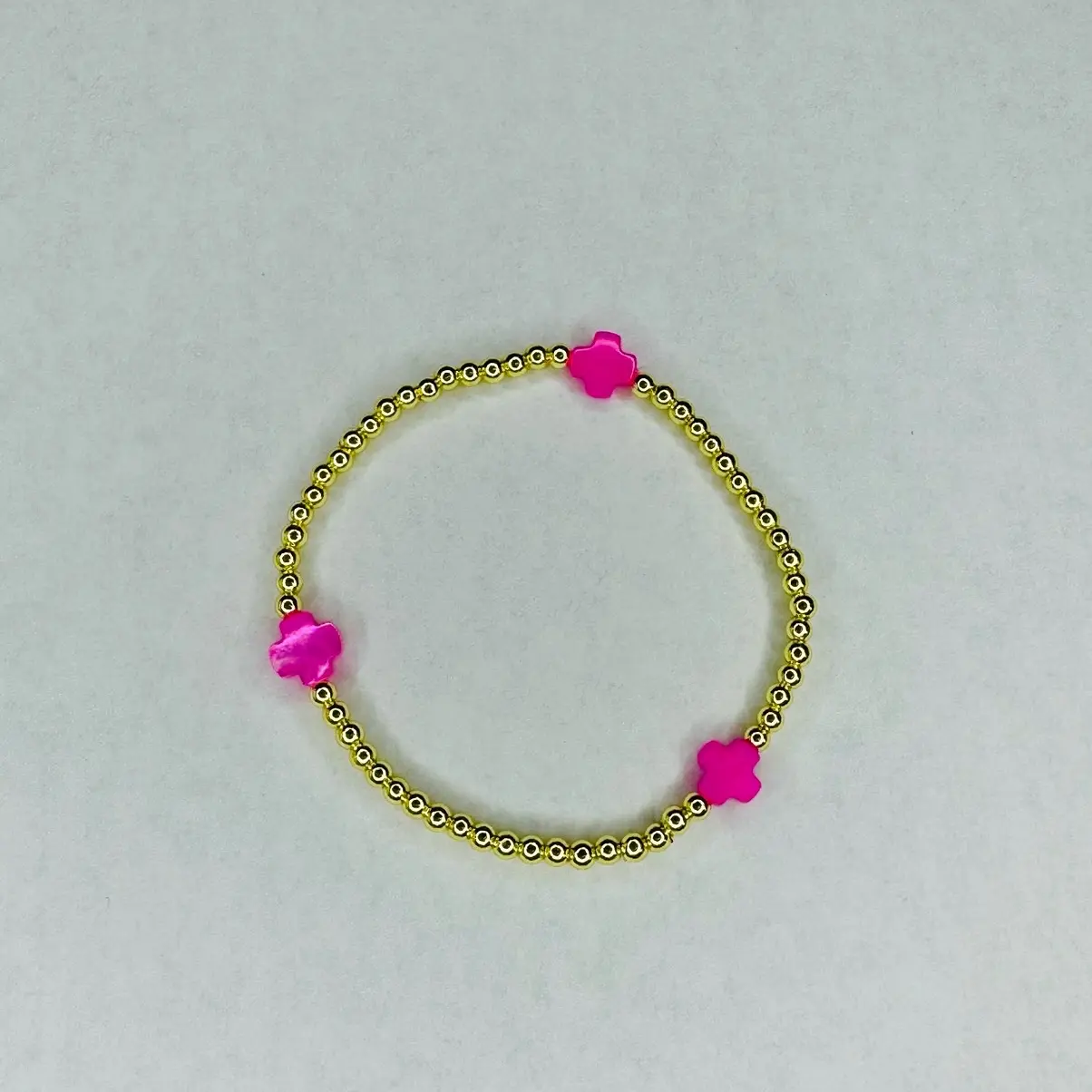 Malibu pearl bracelet, 6.5” stretchy bracelet with 3mm round gold plated hematite beads and 3 8mm hot pink color mother of pearl cross beads