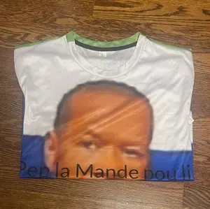 T-Shirt with Unique Design Featuring "Pep la Mande Pou Li" Text and Distinctive Color Scheme