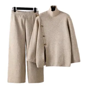 “Elevate your loungewear game with this sophisticated two-piece knit set in a warm beige tone. The high-neck sweater features a unique asymmetrical button-down design and relaxed, oversized sleeves for a modern, chic look. Paired with wide-leg pants for u