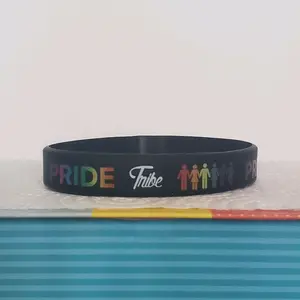 LGBTQIA+ PRIDE Silicone Wristband showing "PRIDE Tribe" all around the band. Rainbow letters over a black band. Our original and discontinued line, adopt yours today before it's sold out. = )