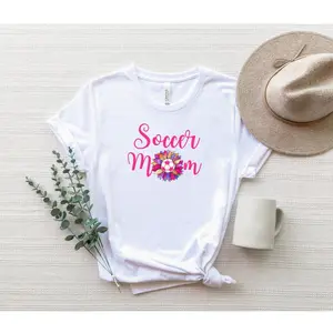 Women's soccer mom appreciation and motherhood Graphic T-Shirt - Short Sleeve Crew Neck Regular Fit Casual Wear | Soft & Breathable Fabric, Durable Print, Everyday Comfort, Machine Washable, casual and feminine with floral design flat lay lifestyle setup