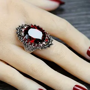 A fashionable women's silver-plated oval ring adorned with a red artificial garnet stone, featuring a classic, free-spirited, and elegant design.