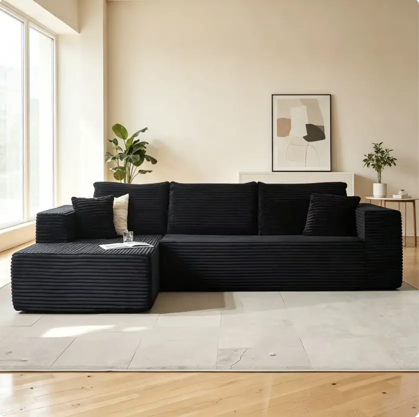 Black corduroy L-shaped sectional sofa with vertical stripe texture. Oversized square armrests and deep seat offer incredible lounging comfort. Modern minimalist silhouette, flexible chaise layout, brings sleek cozy style to contemporary living rooms.