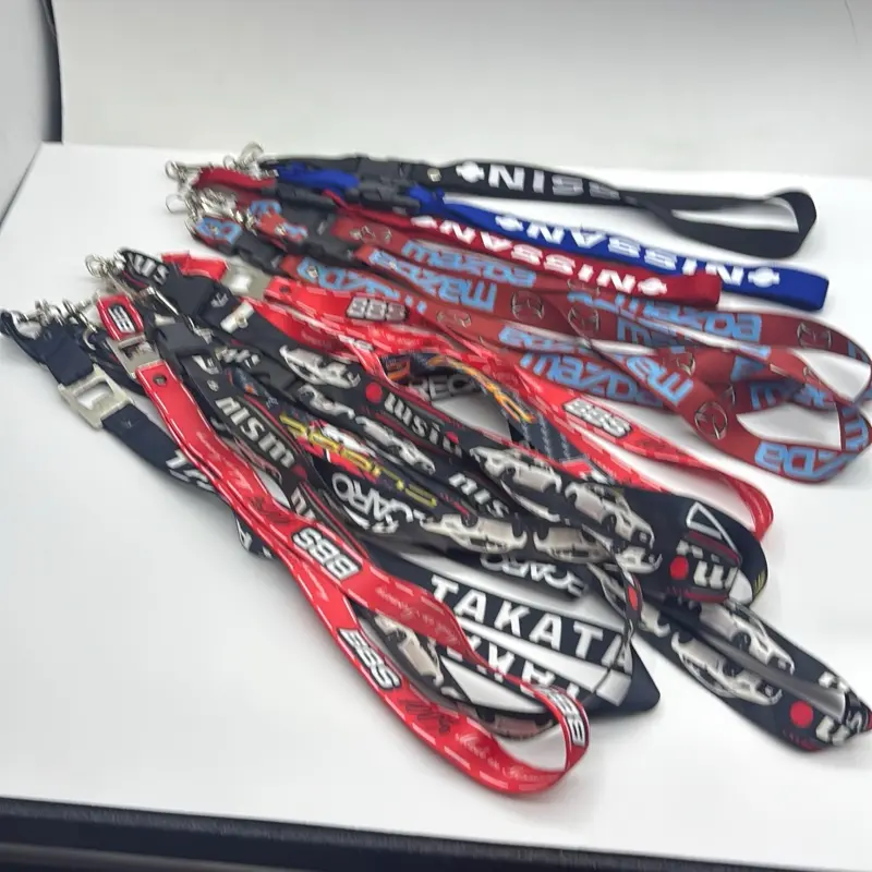 The lanyards feature high-performance motorsports motifs, including brands such as Nissan and Nismo. They are equipped with a metal snap hook and a plastic quick-release buckle.