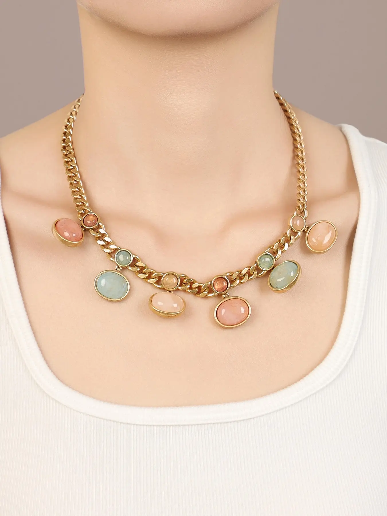 A vintage vintage antique gold colored treasure pendant Cuban chain item, with a colorful oval colored treasure pendant on the chain body, suitable for daily wear, vintage styling, and light fashion scenes.