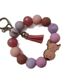 Keyring with Small Cream Colored Highland Calf Surrounded by Multicolored Beads Also Attached is a Tassel and a Lobster Claw