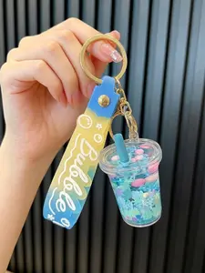 A keychain pendant in the shape of a milk tea cup with flowing oil sand simulation, suitable for daily wear, vacations, dates, and other occasions, and also a delightful and exquisite small gift.