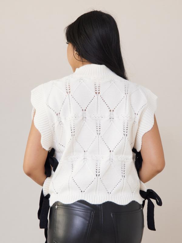 Wishlist Vest - White comfy cable knit sweater vest with scallop details, black side bows, and a turtleneck, offering a slightly oversized fit
