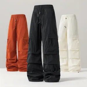 American high-street orange cargo parachute pants made of lightweight quick-dry nylon; drawstring wide-leg pants with multiple pockets and ruched cuffs; unisex streetwear long pants suitable for dancing; ideal for spring/summer outdoor stage outfits.