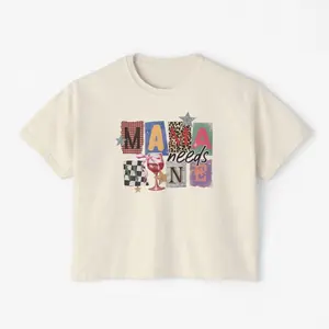 Chic boxy tee with playful 'Mama Needs Wine' graphic. Perfect for laid-back moms, featuring a retro patchwork design and a wine glass print. Great for casual outings or as a gift