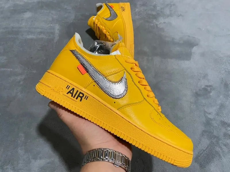 Unisex deconstructed hip-hop low-top sneakers in solid bright yellow leather, brushed silver side patch & tiny orange tag, perforated breathable toe, shock-absorbing full yellow rubber outsole.
