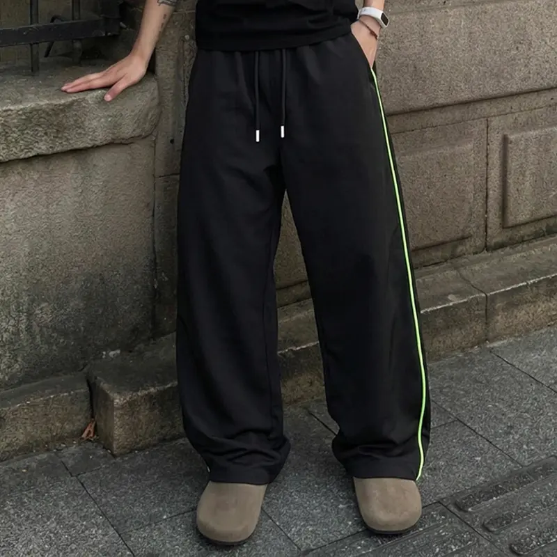 Single piece wide-leg athletic pants with fluorescent green side stripes, American street style, elastic high-waisted design, suitable for adult men’s city outings and holiday travel, the bright stripes enhance overall outfit visibility. sohochic