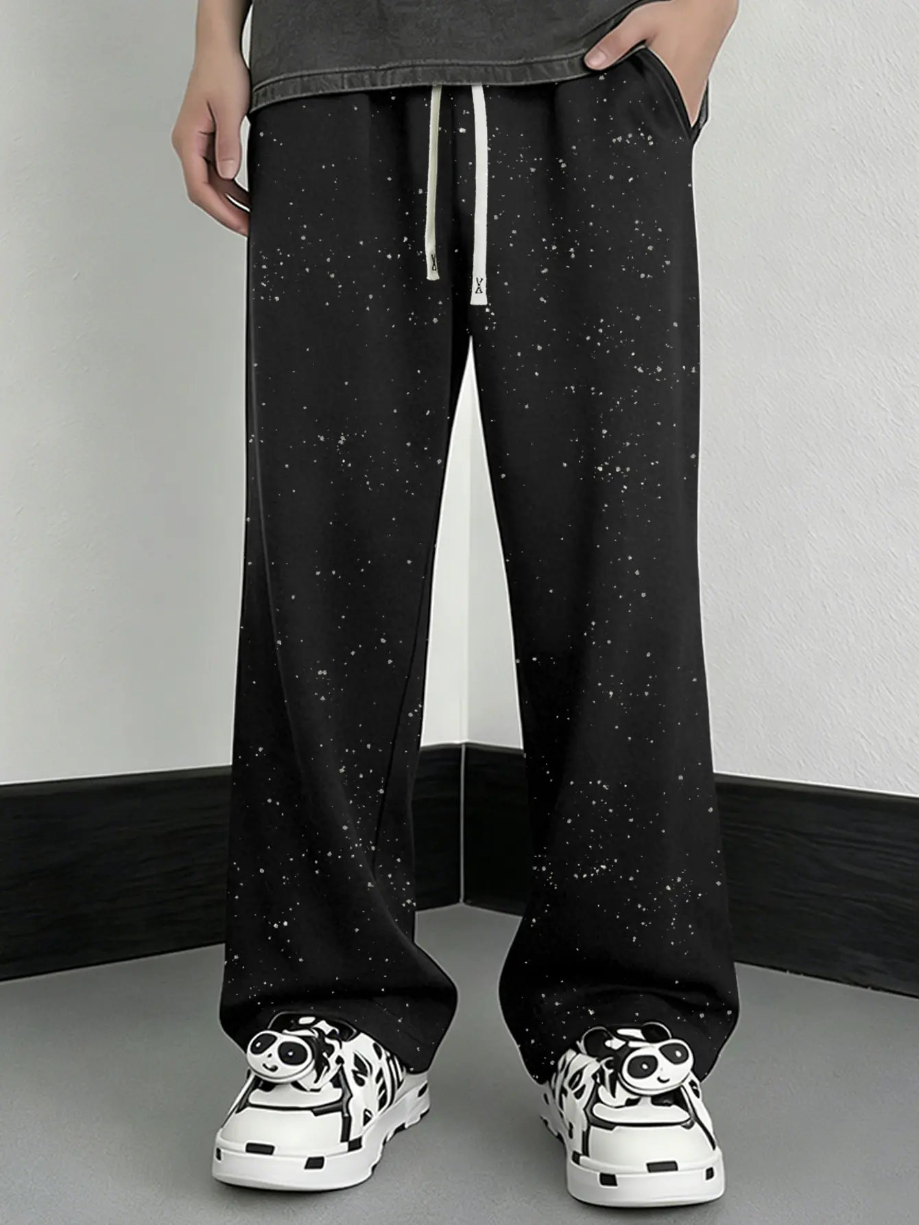One black men’s knit sweatpants in a casual American style, featuring an allover fine white dot starry sky print paired with off-white drawstring details and symmetrical side pockets. Suitable for men when going out shopping, exploring shops, and travelin