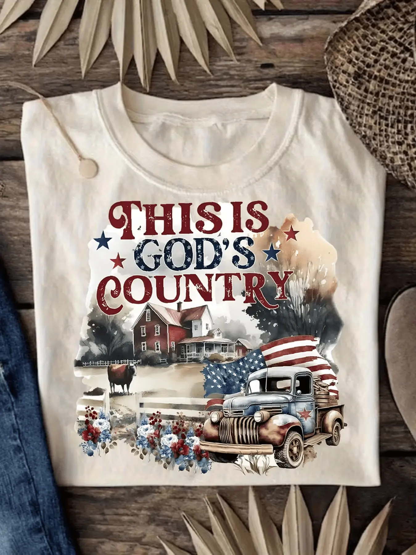 Patriotic Pattern T-Shirt- Bright Red and Blue "This Is God's Land" Design Featuring Stars and a Pastoral Scene Including a Red Farmhouse and a Vintage Truck |   Perfect for Celebrating Rural Charm and American Pride |   It Is an Ideal Gift for Co