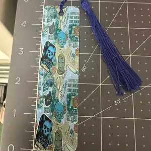 Lights out themed metal bookmark with tassel