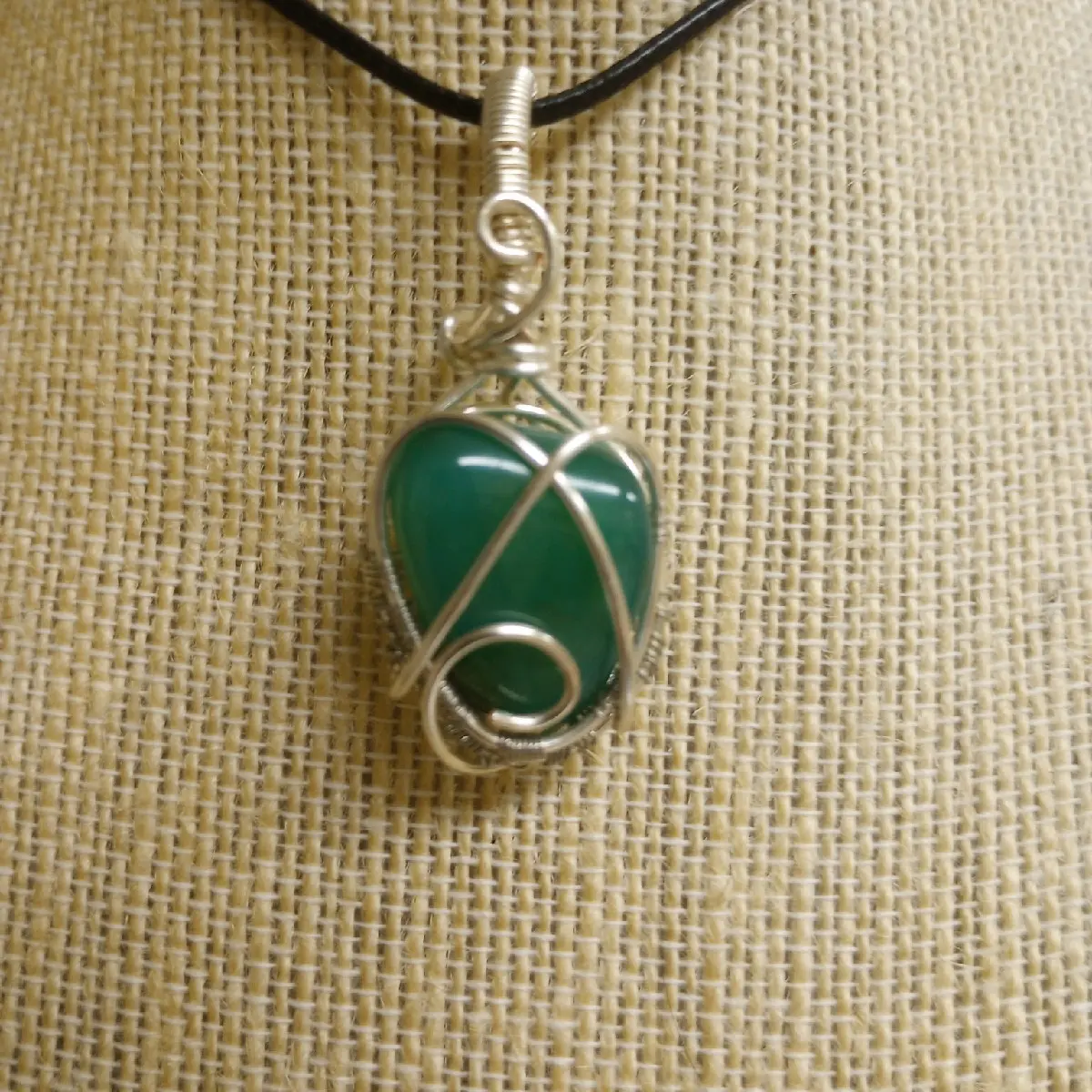 Natural polished agate, dyed for color, bright teal. Wrapped by hand in silver. Natural colorations are seen in the stone. Pendant comes with corded necklace.  Matching pendant and earring sets are available with stones in stock, inquire if interested.