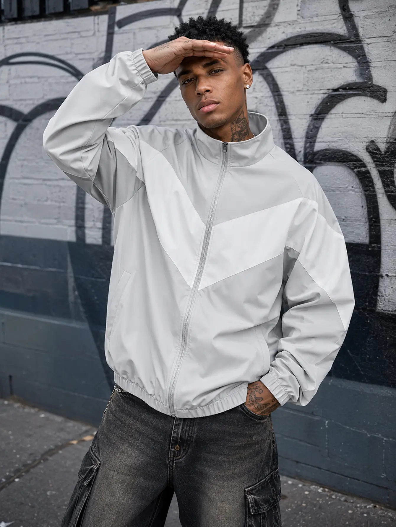 Men’s light gray jacket with a V-shaped contrast design and stand collar, made from windproof woven fabric. Loose drop-shoulder fit with a symmetrical white V-shaped panel detail, elastic cuffs and hem, retro sports casual jacket.
