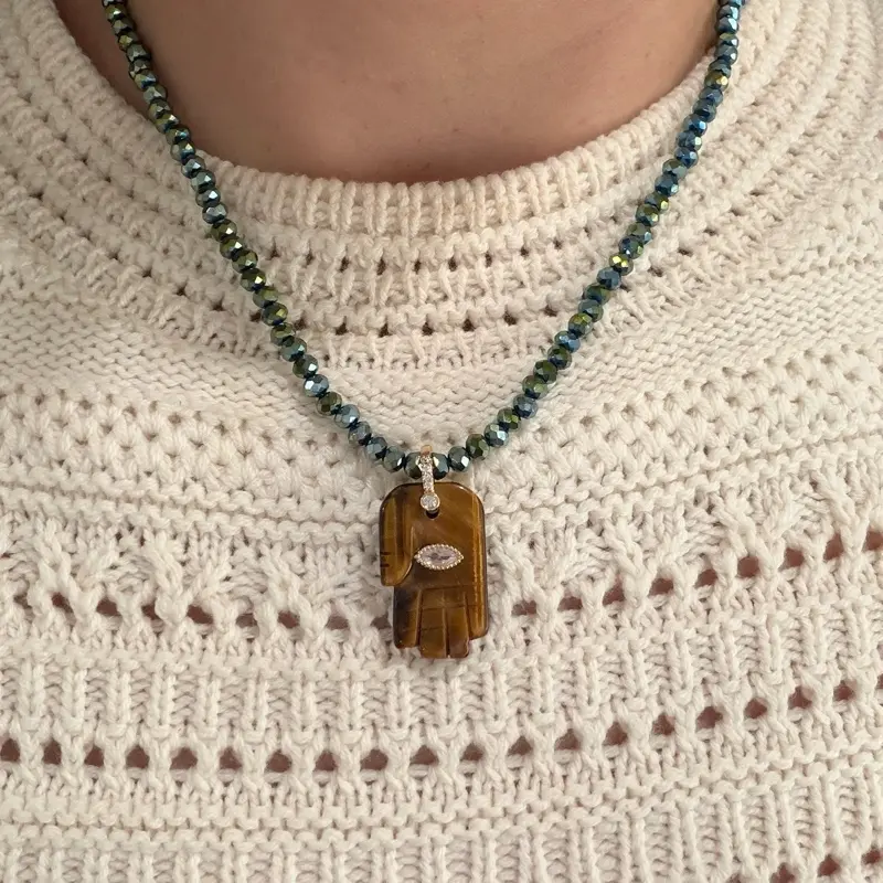 Beautiful iridescent crystal necklace featuring a brown stone Hamsa hand charm, believed to attract good fortune and protection.