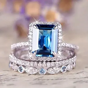 A set of three wedding rings for brides featuring a four-prong setting with a square synthetic aquamarine gemstone, perfect for engagement parties and stylish jewelry.