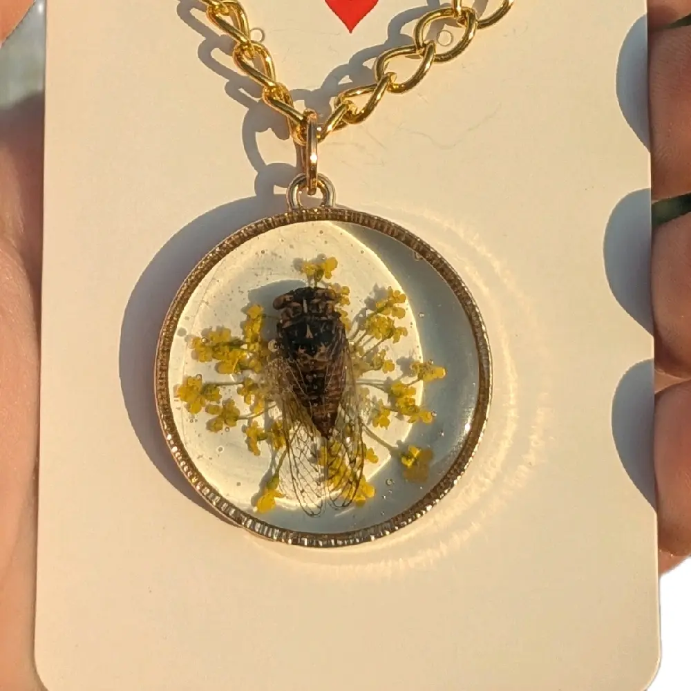 Mini Cicada Necklace with Unique Design featuring a Cicada and Yellow Flowers in a Circular Frame with a gold chain