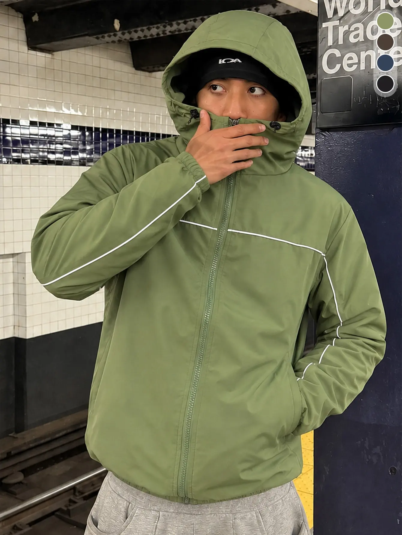 Men’s army green hooded windproof jacket with a high collar that provides face protection and can be tightened; white reflective trim along all edges; elastic cuffs; woven fabric; American functional style commuter outerwear.