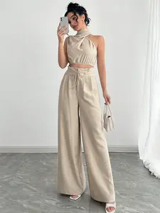 Women’s apricot two-piece set with asymmetrical halter neckline: cotton-linen top that reveals the waist + high-waisted flared pants with a pouf silhouette — refined, mature-style ensemble